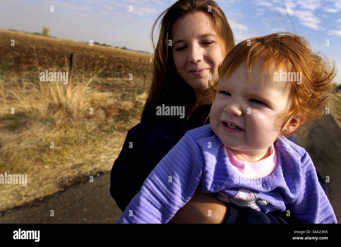 Renee Clopton (991–4355) hält am Freitag, 7. November 2003, ihre jüngste Tochter Savanna, 1, auf der Einfahrt ihrer Farm im ländlichen Elverta fest. Hinter ihr sind 900 Häuser eines Wohnprojekts geplant. Bewohner von Elverta, die den ländlichen Lebensstil mögen, sind gegen ein 4.500 geplantes Wohnprojekt in ihrem Gebiet, das derzeit als Wohngebiet/Landwirtschaft bezeichnet wird. Das Thema ist derzeit Gegenstand einer Reihe von Anhörungen vor der Sacramento County Policy Commission. Sacramento Bee/Brian Bär/ZUMA Press Stockfoto