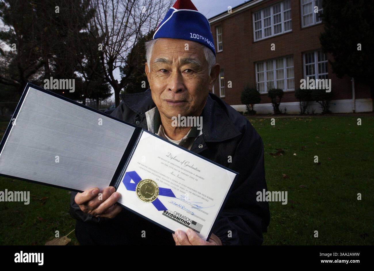 Der 78-jährige Akira Iwatsuru besitzt das High School Diplom, das er 2002 vom Sacramento County Office of Education am Dienstag, den 23. November 2003, außerhalb des ehemaligen Elk Grove High School Wissenschaftsgebäudes in Elk Grove erhielt. Iwatsuru war Schüler an der Elk Grove High School, als er von der Schule entfernt und im Jerome Relocation Center in Arkansas beigesetzt wurde. Später trat er als Internierter in die Armee ein, als er gerade 17 war. Er war Mitglied des 442. Regimentskampfteams im Zweiten Weltkrieg. Das Gebäude hinter Iwatsuru ist heute Teil der Joseph Kerr Middle School. Stockfoto