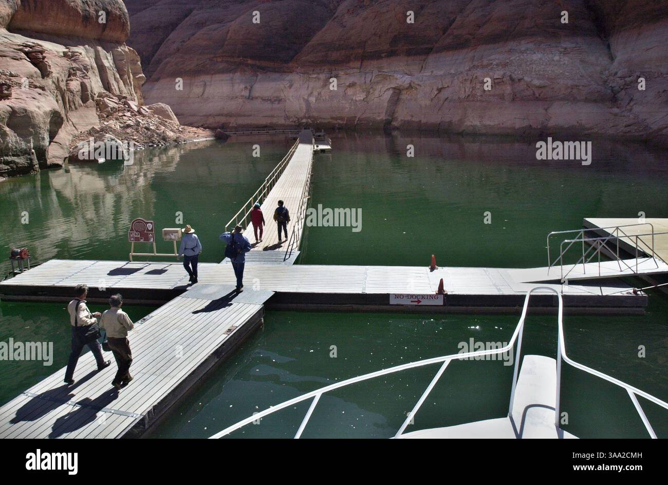 Besucher des Rainbow Bridge National Monument kommen mit dem Boot an, gehen über ein schwimmendes Dock und wandern dann 1,5 km zum 290' hohen Naturbogen, Mittwoch, 12. März 2003. Touristen, die am beliebtesten Ort am Lake Powell waren, haben früher in Sichtweite des Denkmals mit dem Boot gefahren. Sacramento Bee/Jay Mather/ZUMA Press Stockfoto