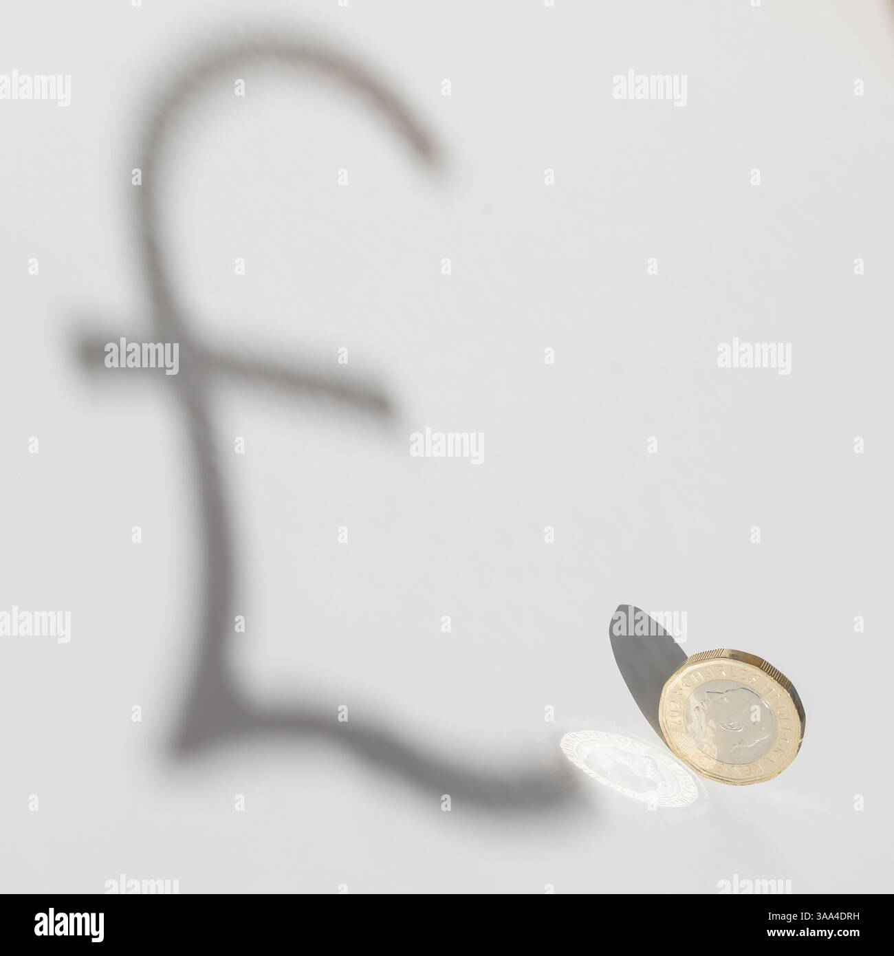 Britische ein-Pfund-Münze wirft einen Schatten in Form eines Pfund-Symbols – visuelle Metapher für Währungswert, Wirtschaft und Finanzkonzept Stockfoto