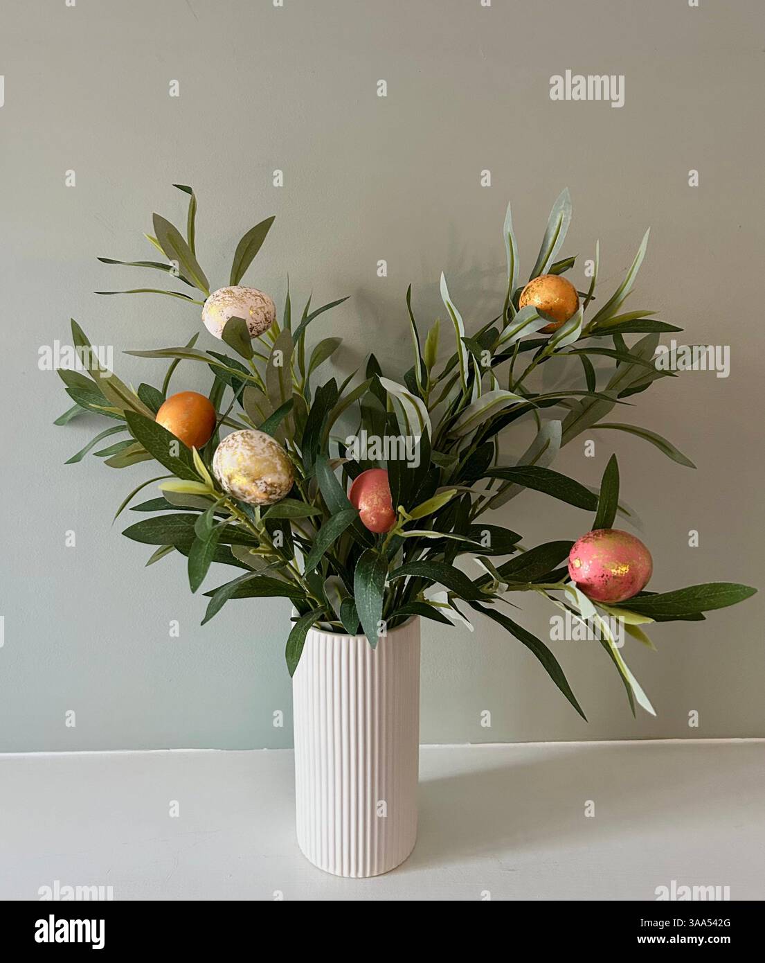 Farbenfrohe Ostereier inmitten grüner Blätter schaffen eine festliche und lebhafte Frühlingsszene. - Smartphone-aufgenommenes Stockfoto
