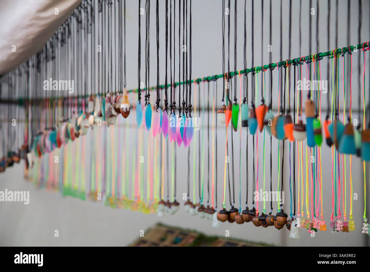 Handgefertigter Schmuck mit künstlichen bunten Steinen sowie künstlichen Eicheln auf schwarzen Fäden Stockfoto
