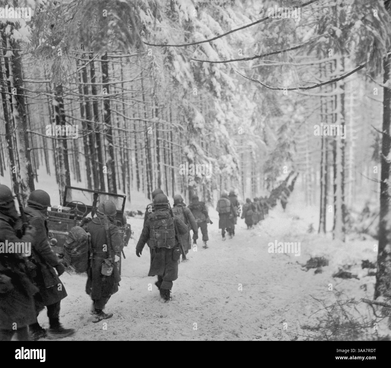 AM 24. Januar 1945 marschieren amerikanische Soldaten des 289. Infanterieregiments der US-Armee auf der schneebedeckten Straße Stockfoto