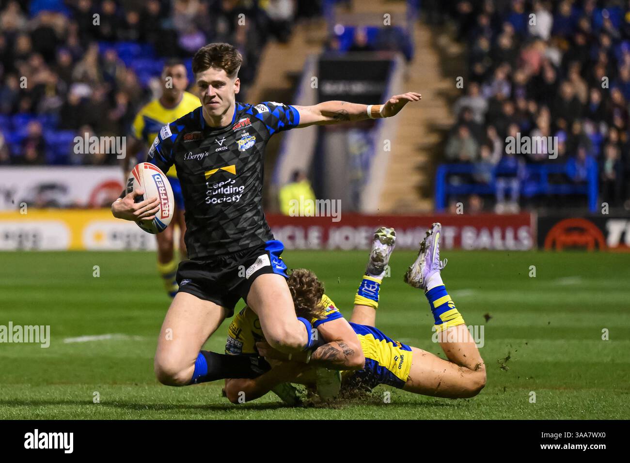 WARRINGTON, ENGLAND - 28. MÄRZ 2025: Riley Lumb von Leeds Rhinos wird während der Betfred Super League Runde von Arron Lindop von Warrington Wolves bekämpft Stockfoto