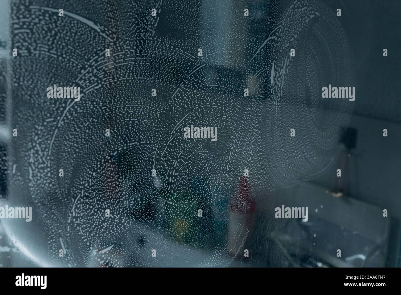 Сlose auf der Glasoberfläche, die mit Seifenschaum bedeckt ist, mit einem Schwamm, der sie sauber abwischt und die Textur hervorhebt. Hochwertige Fotos Stockfoto