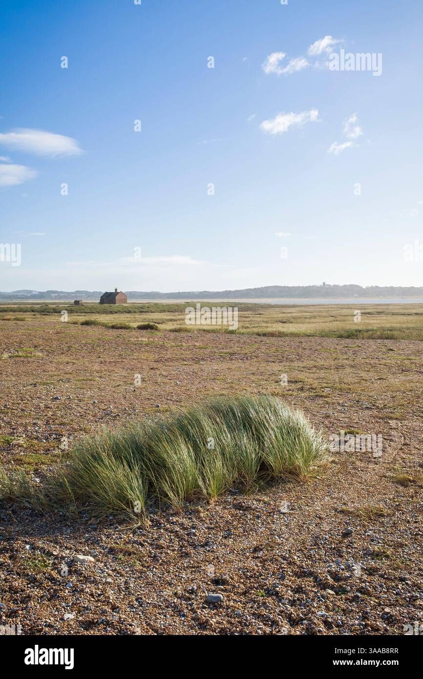 Remote Watch House im Naturschutzgebiet Marrams, Blakeney Point, Norfolk, Großbritannien, umgeben von Feuchtgebieten an der Küste, Kieselstrand und Gras unter einem blauen s Stockfoto