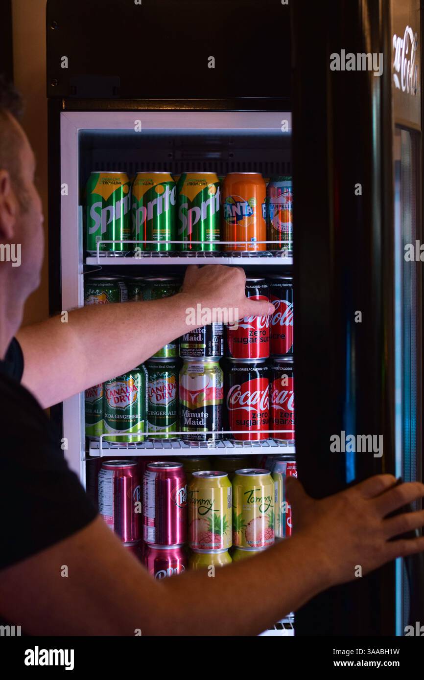 Die Hand des Mannes greift in den Kühlschrank im Restaurant, um eine Dose mit alkoholfreiem Getränk zu holen Stockfoto