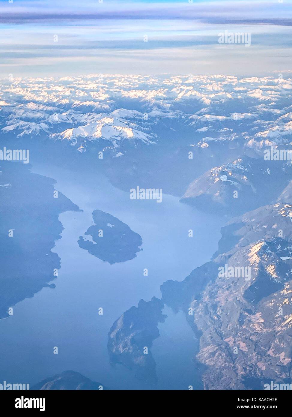 Aus der Vogelperspektive auf einen ruhigen Bergsee mit kleinen Inseln und umliegenden schneebedeckten Gipfeln. Ideal für Natur-, Reise- und Landschaftskonzepte. Stockfoto