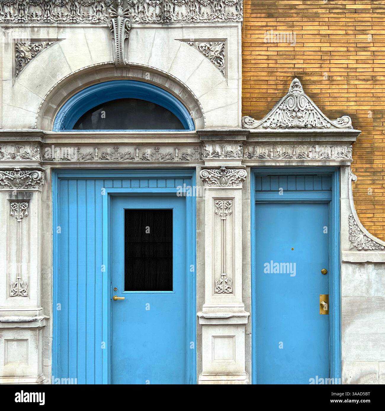 Zwei leuchtende himmelblaue Türen vor einer detailreichen klassischen Steinfassade und einer gelben Ziegelmauer in Chicago - Smartphone-aufgenommenes Stockfoto