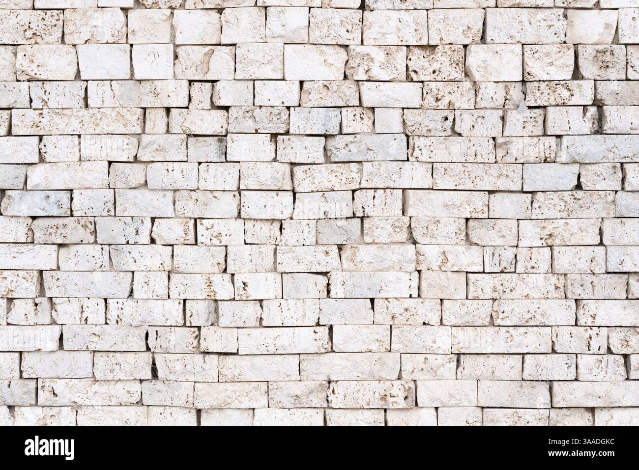 Wandstruktur oder Hintergrund mit freiliegenden hellen Steinen, die traditionelle Handwerkskunst zeigen. Perfekt für architektonische, historische und texturale Designs Stockfoto