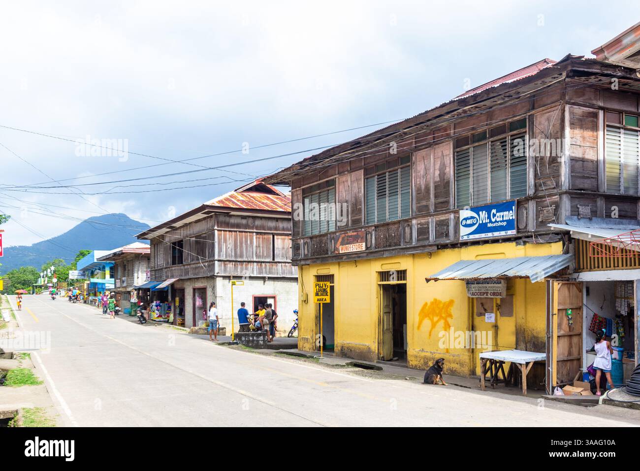Eine Reihe von philippinischen Häusern säumt eine ruhige Straße in einer kleinen Stadt Camiguin, die traditionelle Architektur und lokalen Charme bietet Stockfoto Eine Reihe von philippinischen Häusern säumt eine ruhige Straße in einer kleinen Stadt Camiguin, die traditionelle Architektur und lokalen Charme bietet Stockfoto