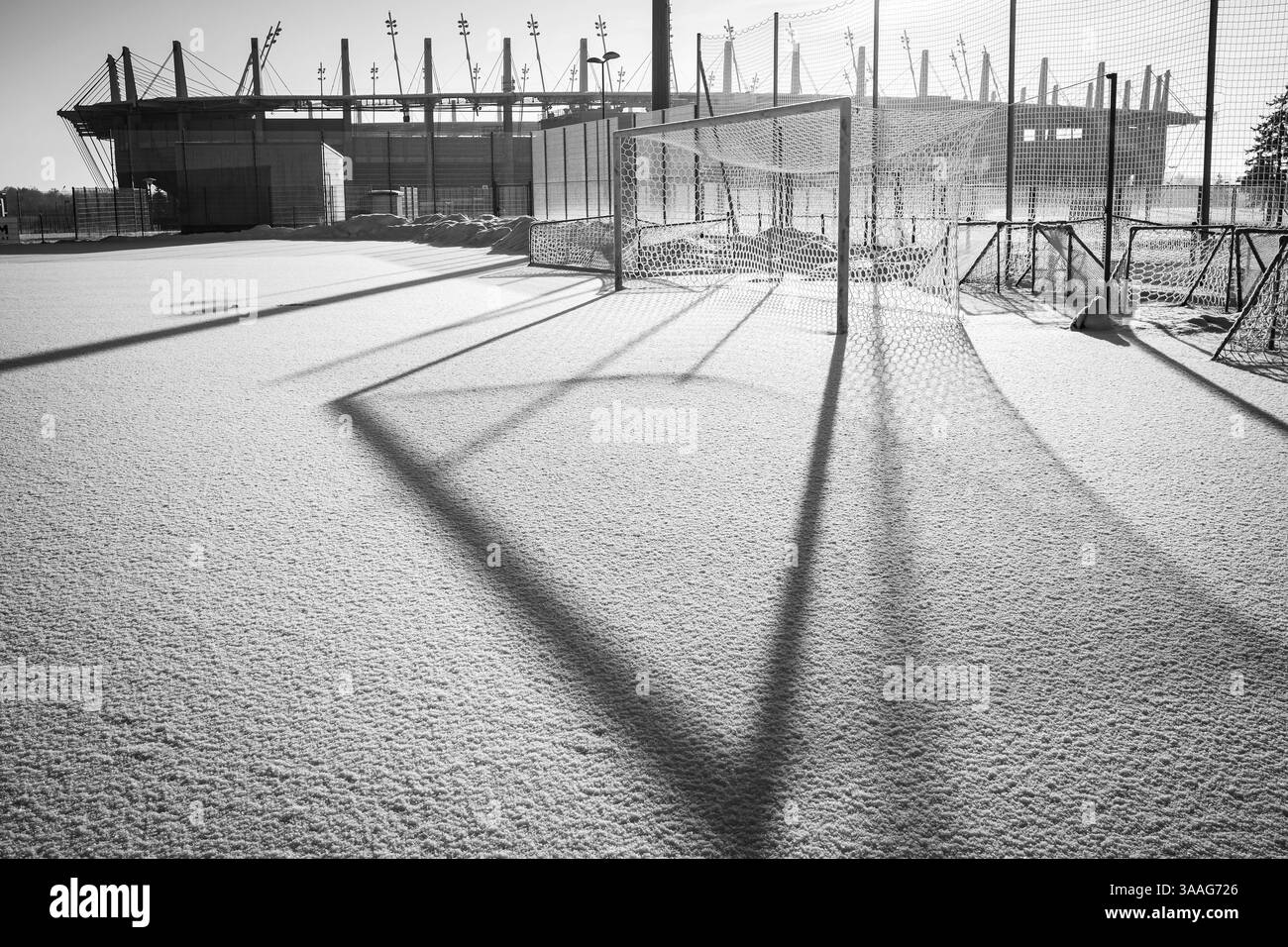 Gefrorener Fußballplatz mit Schnee und Stadion im Hintergrund Stockfoto