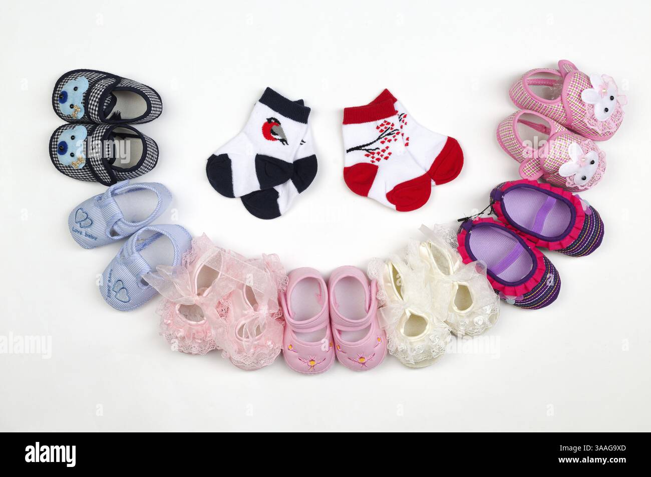 Kinderschuhe und -Socken wurden halbkreisförmig auf hellem Hintergrund gelegt Stockfoto