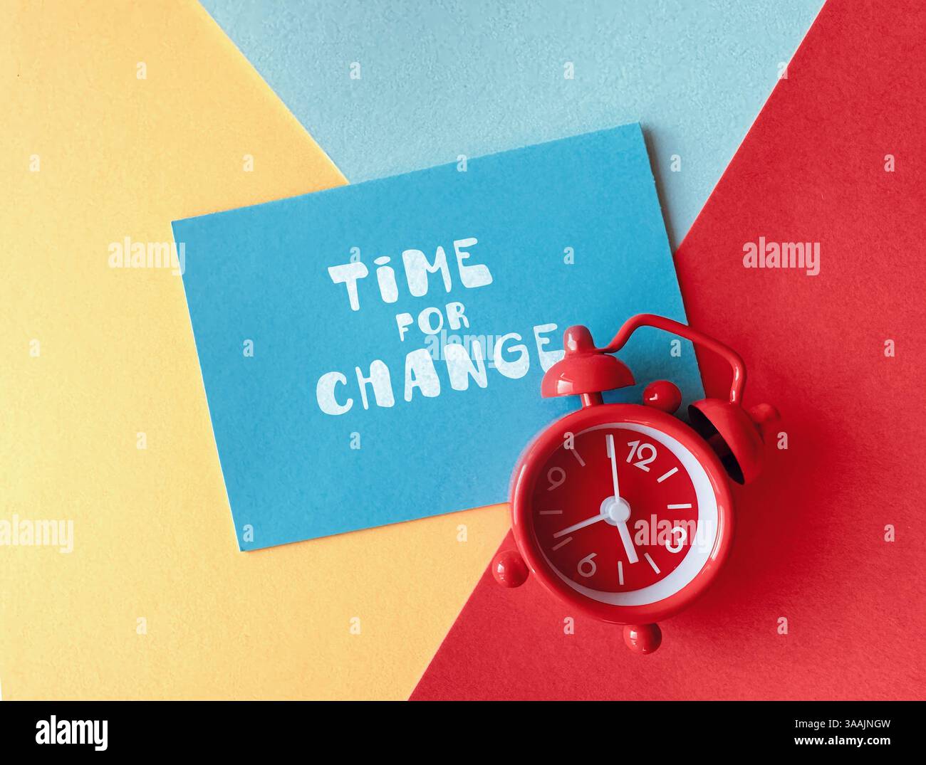 Roter Wecker und blaue Karte mit Text Time for Change auf farbenfrohem geometrischem Hintergrund, Konzept der Motivation und Transformation. Stockfoto