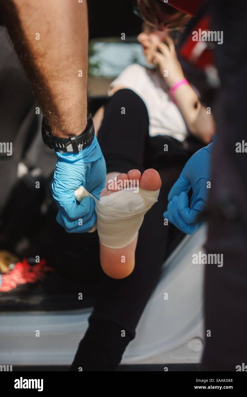 Ein Arzt verbindet das Bein eines verwundeten Mädchens und behandelt Kallus von einem langen Spaziergang. Stockfoto