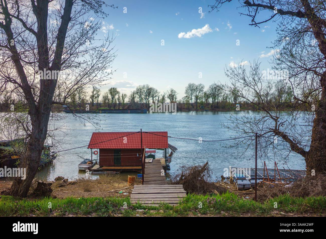 Kleine Holzhäuser am Fluss Sava in Serbien. Früher Frühling, bewölkt, aber schönes Wetter. Stockfoto