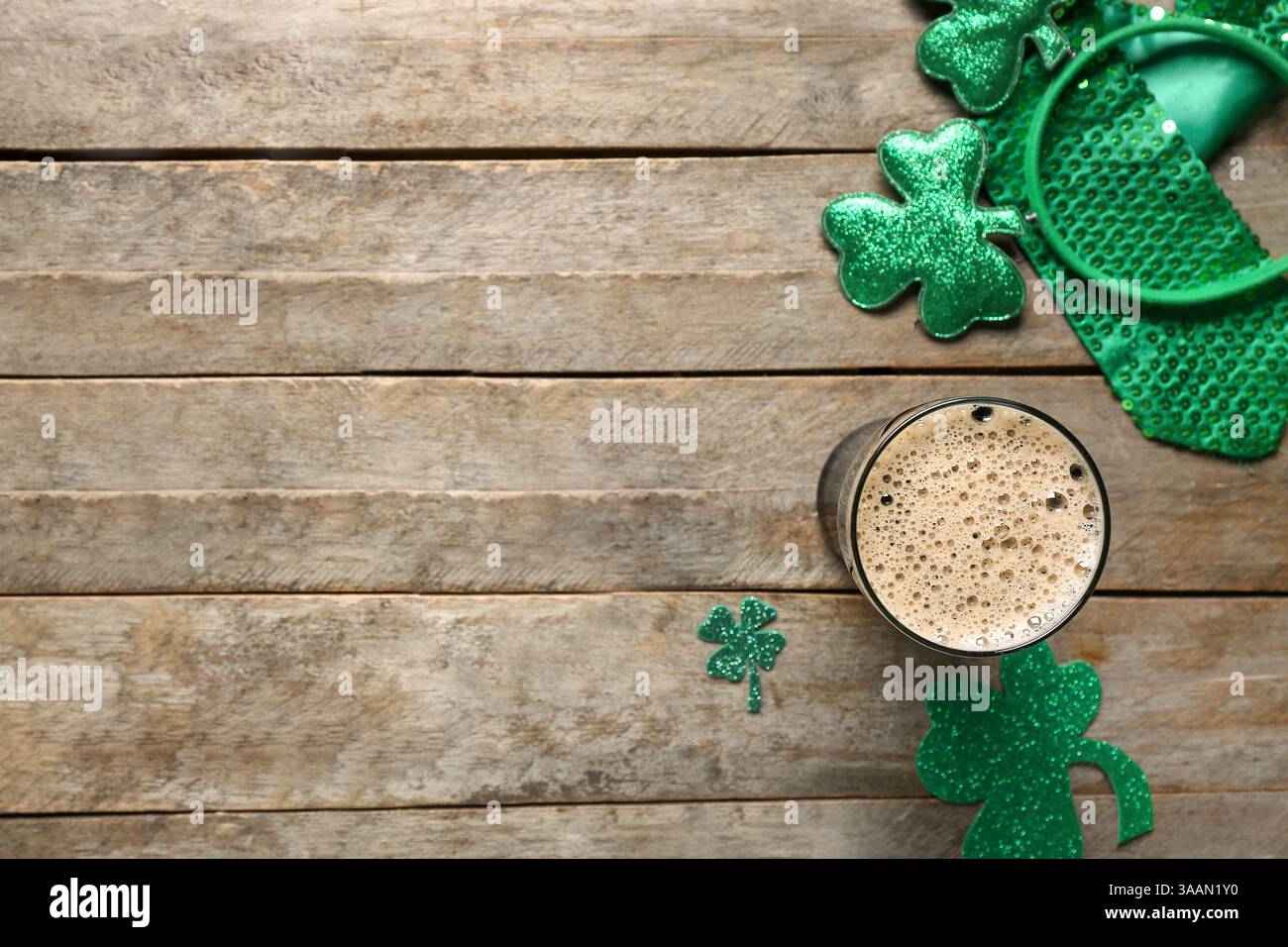 Ein Glas dunkles Bier mit Krawatte und Dekor für die Feierlichkeiten zum St. Patrick's Day auf hölzernem Hintergrund Stockfoto