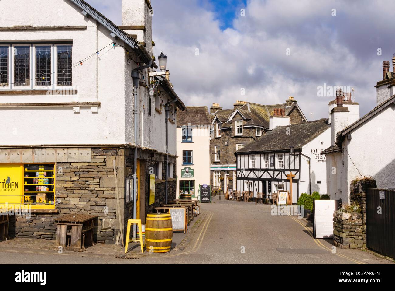 Blick entlang der schmalen Straße zum Queens Head Village Pub im Lake District National Park. Hawkshead, Cumbria, England, Großbritannien. Stockfoto