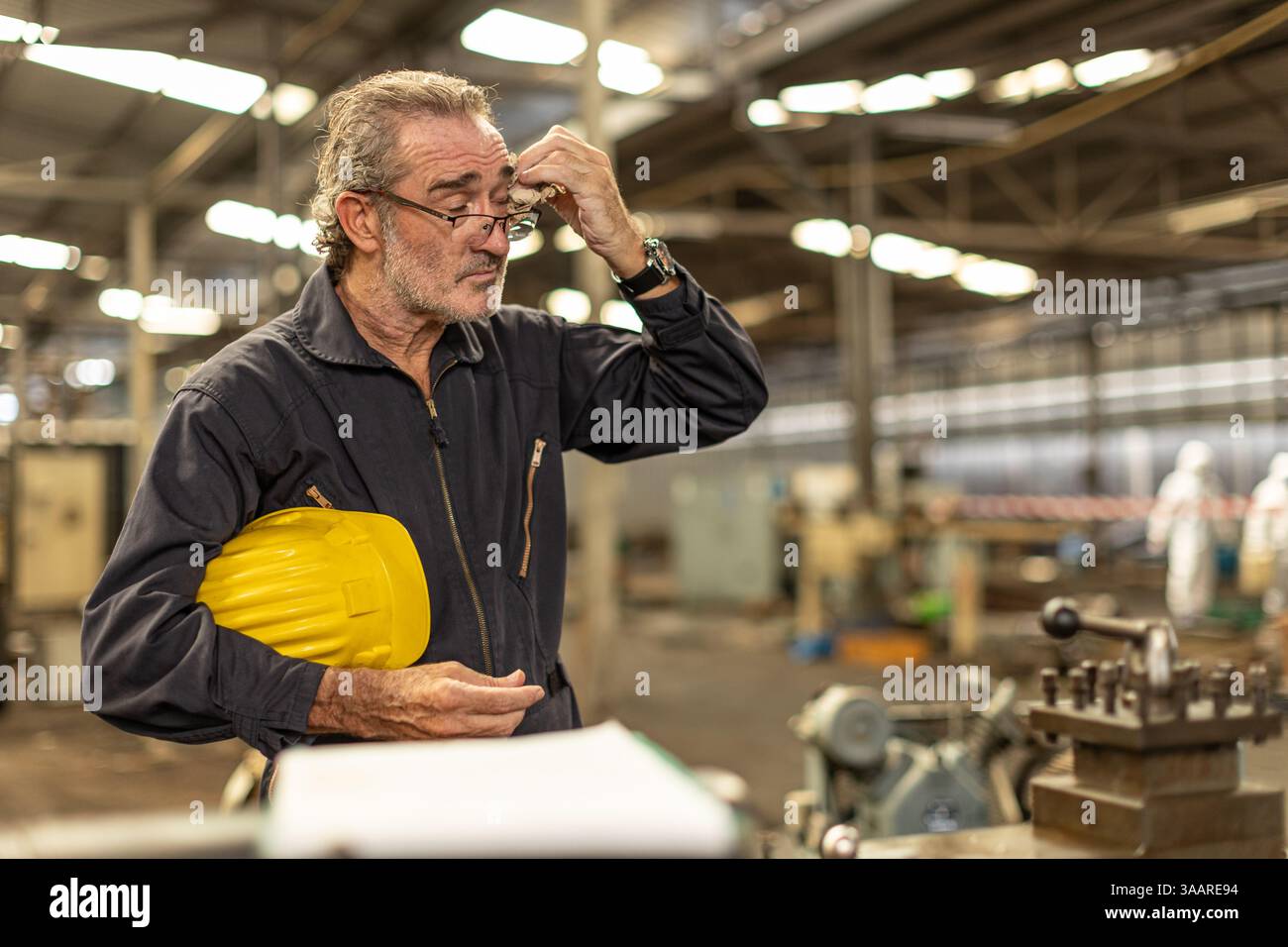 Seniorenarbeiter müde erschöpfte Kopfschmerzen leiden unter harter Arbeit in einer Fabrik der Schwerindustrie. Stockfoto