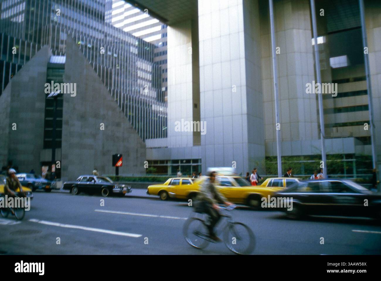 Lexington Avenue, New York Mitte der 80er Jahre. Am Fuße des Citicorp Center, das auf den Schlitzen ruht, und der Peterskirche auf der linken Seite, unterhalb des Wolkenkratzers. Einzigartiges Gebäude, das unterwegs mit Minolta-Kamera und FUJI-Film aufgenommen wurde. Gelbe Taxis und schnell fahrende Biker Stockfoto
