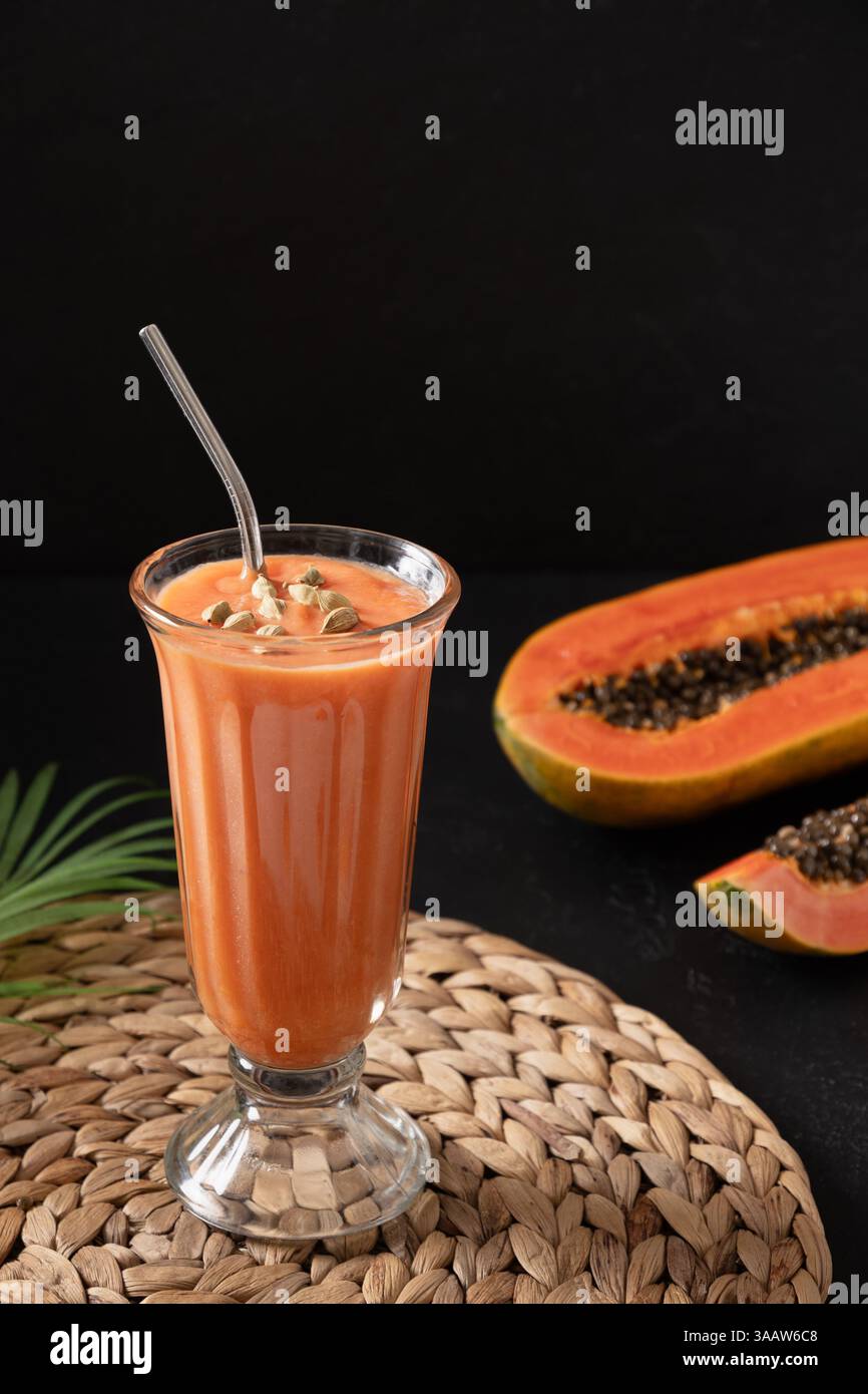 Asiatische traditionelle Papaya auf dunklem Hintergrund. Frisches Kaltgetränk mit Joghurt, Wasser, Gewürzen, Obst und Eis. Beliebtes Getränk in Indien und Sri Stockfoto