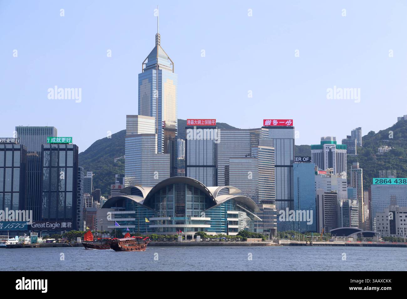 Weitläufiger Blick von der Avenue of Stars in Richtung Hong Kong Convention Centre und Victoria Harbour mit berühmten roten Segelbooten (Hong Kong) Stockfoto