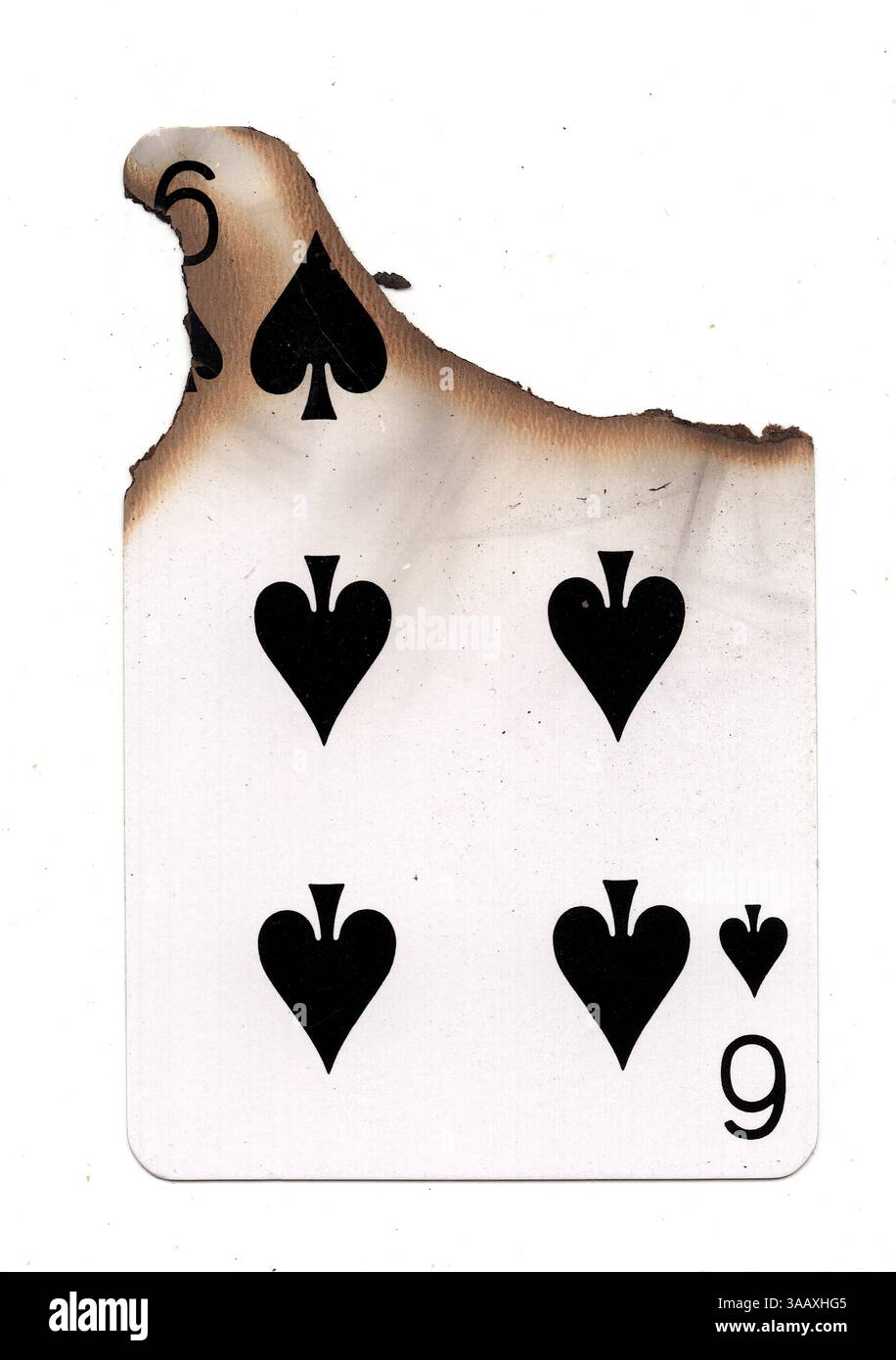 Eine teilweise verbrannte Spielkarte im Pik-Anzug auf weißem Hintergrund. Stockfoto