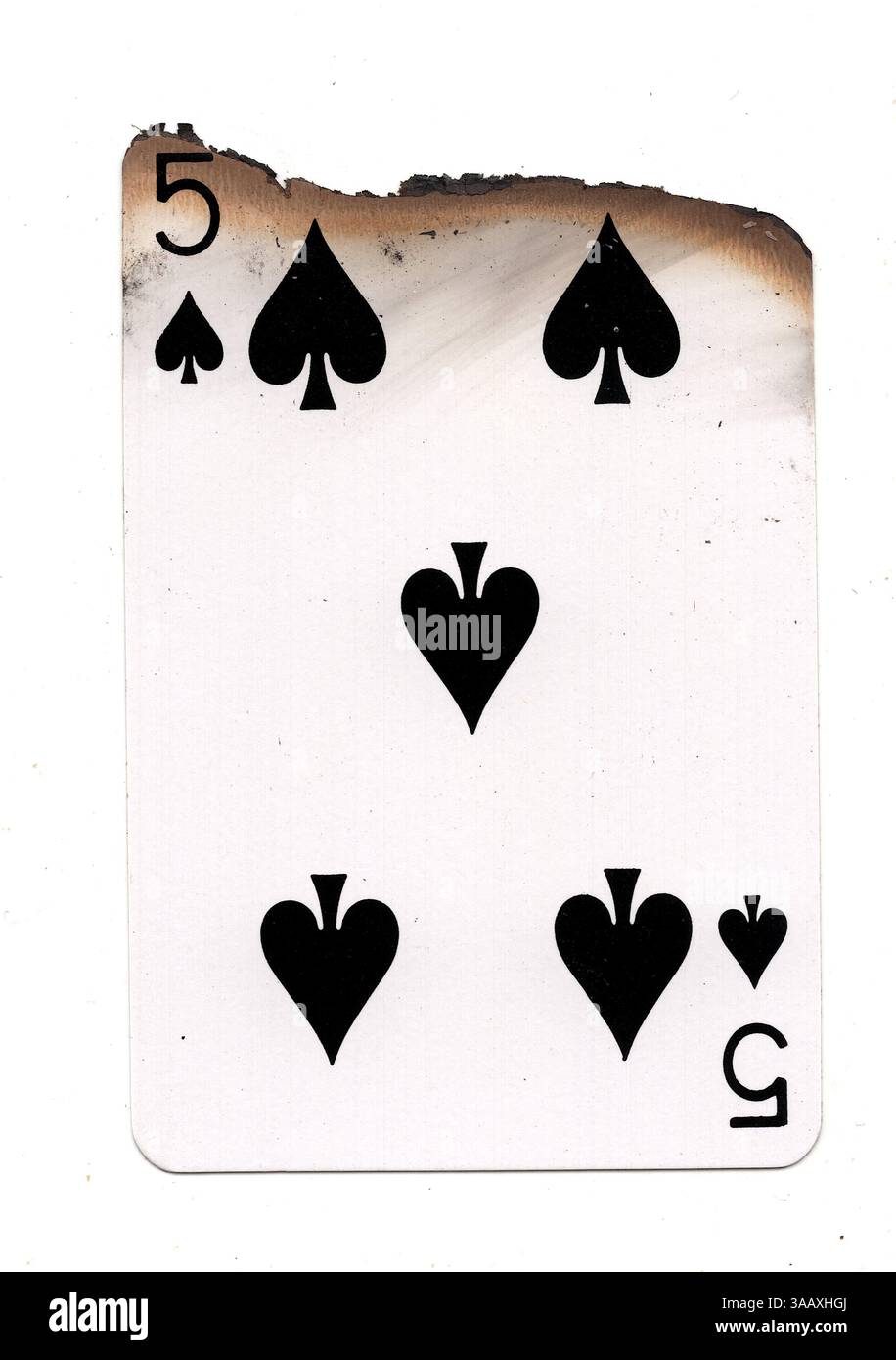 Eine teilweise verbrannte Spielkarte im Pik-Anzug auf weißem Hintergrund. Stockfoto