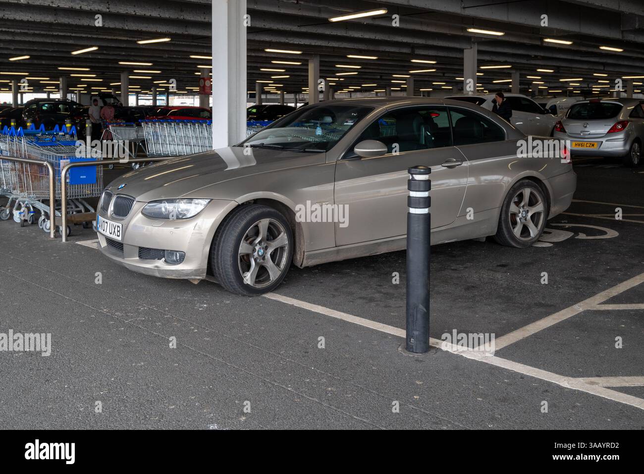 Wie man ein Auto nicht parkt, hat dieser BMW Fahrer sein Auto achtlos in einem Behindertenparkplatz ohne blaues Schild und über die Warteschlangen gelassen. März 2025. Stockfoto