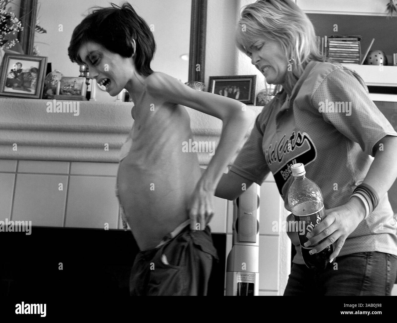 26. April 2006 – Sacramento, Kalifornien, USA – DEREK MADSEN, 11, hat einen letzten Energiesturm, nachdem CYNDIE FRENCH (seine Mutter) tagelang Mahnwache am Bett gehalten hat. Sie hilft ihrem quälenden Sohn zu gehen, indem sie seine Hose hochhält, als er in sein Schlafzimmer zurückkehrt. Ein Tumor hat Dereks Magen so weit gedehnt, dass seine Hose nicht mehr passt. Ein weiterer Tumor in seinem Gehirn beeinträchtigt sein Sehvermögen, was die Navigation in ihrem Miethaus erschwert. (Bild: © Renée C. Byer/Sacramento Bee/zReportage.com Via ZUMA Wire) Stockfoto