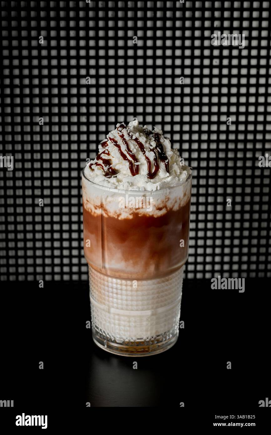 Eiskaffee mit Schlagsahne und Schokolade in einem Glas auf schwarzem Hintergrund Stockfoto
