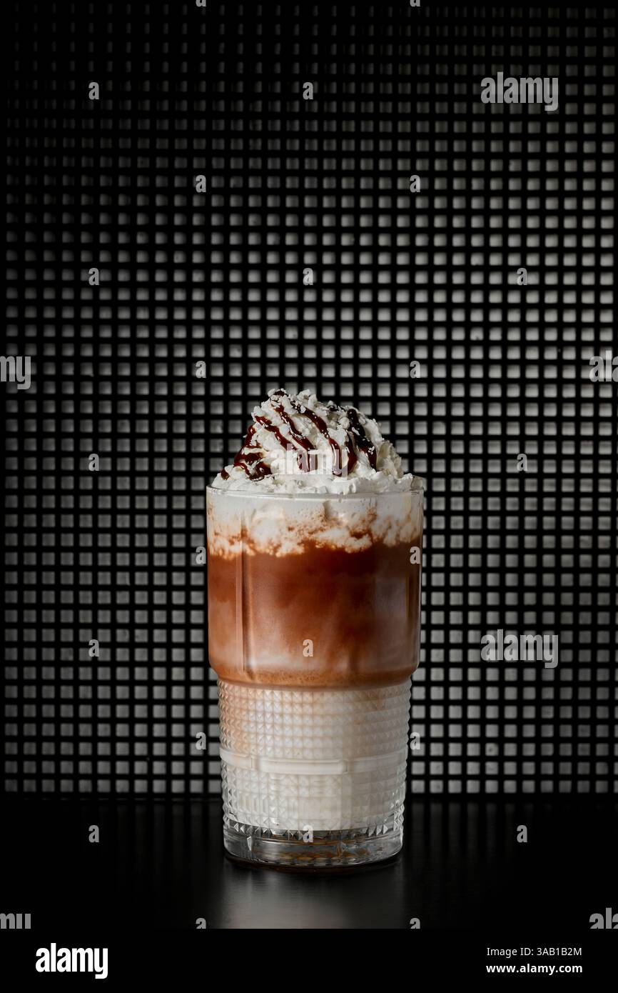 Eiskaffee mit Schlagsahne und Schokolade in einem Glas auf schwarzem Hintergrund Stockfoto