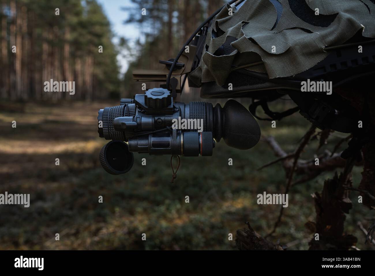 Nachtsichtmonokular montiert auf einem taktischen Helm, Wald im Hintergrund. Stockfoto