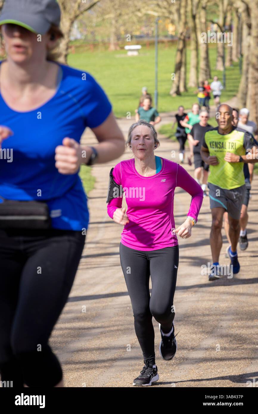 Parkrun am Gladstone Park, London Willesden NW2. Eine Läuferin mittleren Alters beim wöchentlichen Lauf für alle Fähigkeiten. Stockfoto