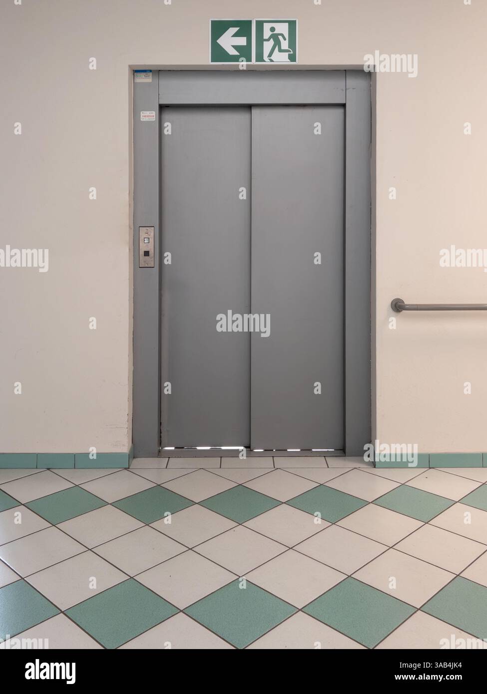 Fahrstuhltür zur Etage mit grünen und weißen, quadratischen Fliesenboden in Rautenmuster Stockfoto