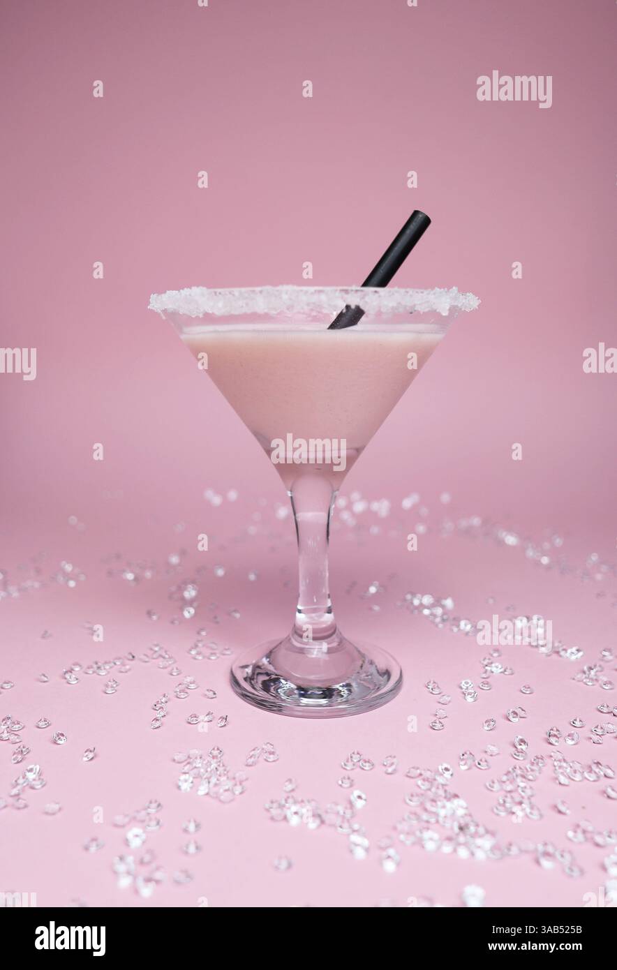 Ein rosafarbenes Getränk in einem Martini-Glas mit Zucker am Rand vor einem hellrosa Hintergrund. Die sanften, pastellfarbenen Töne des Getränks und des Hintergrunds. Stockfoto