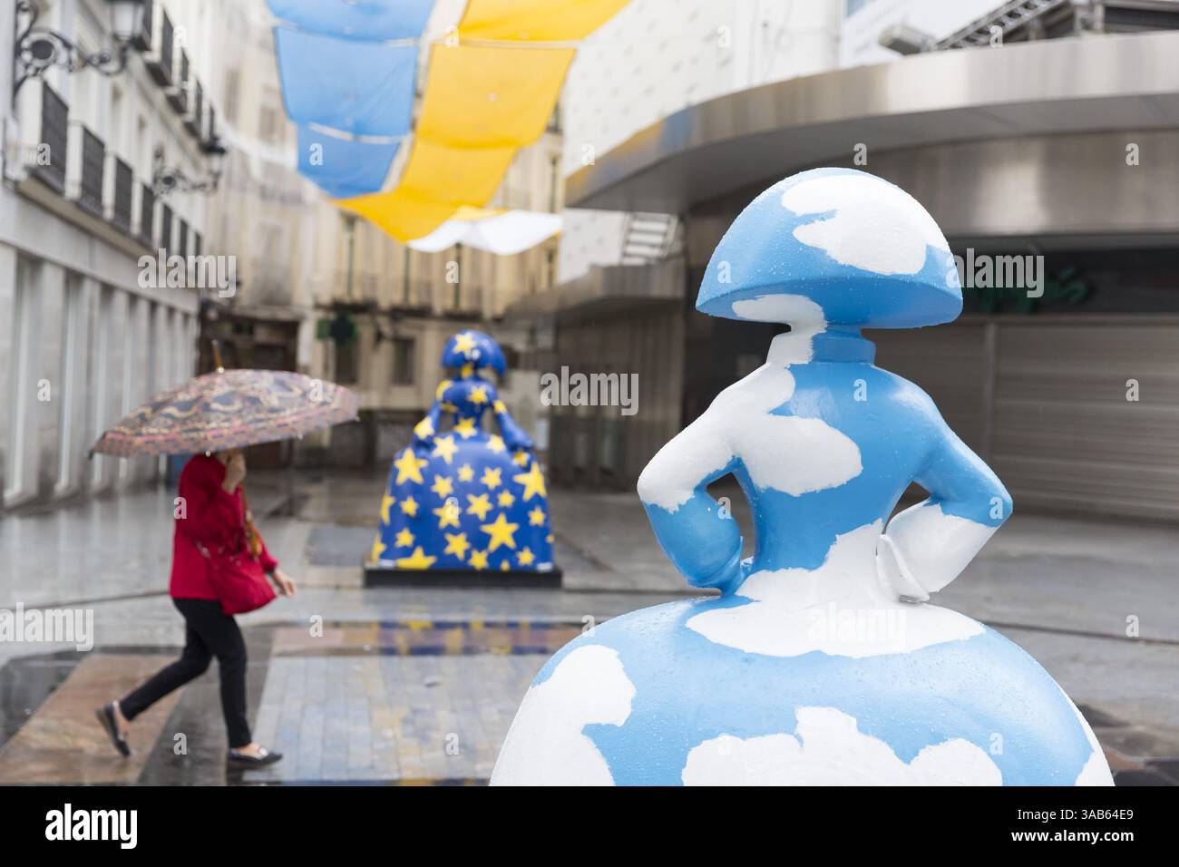 7. Juni 2018 - Madrid, Gemeinschaft Madrid, Spanien - Madrid, Spanien: Frau mit einem Regenschirm passiert zwei „Menina“-Skulpturen entlang der Calle de Preciados. Die Skulpturen sind Teil der „Meninas Madrid Gallery“ zu Ehren der berühmten Meninas von VelÃ¡zquez. Das Projekt wird vom Madrider Stadtrat organisiert und vom Künstler Antonio Azzato geleitet. Die Skulpturen „Cielo de DÃ­a y Cielo de Noche“ wurden von der Künstlerin Agatha Ruiz de la Prada geschaffen. (Bild: © Paul Gordon via ZUMA Wire) Stockfoto
