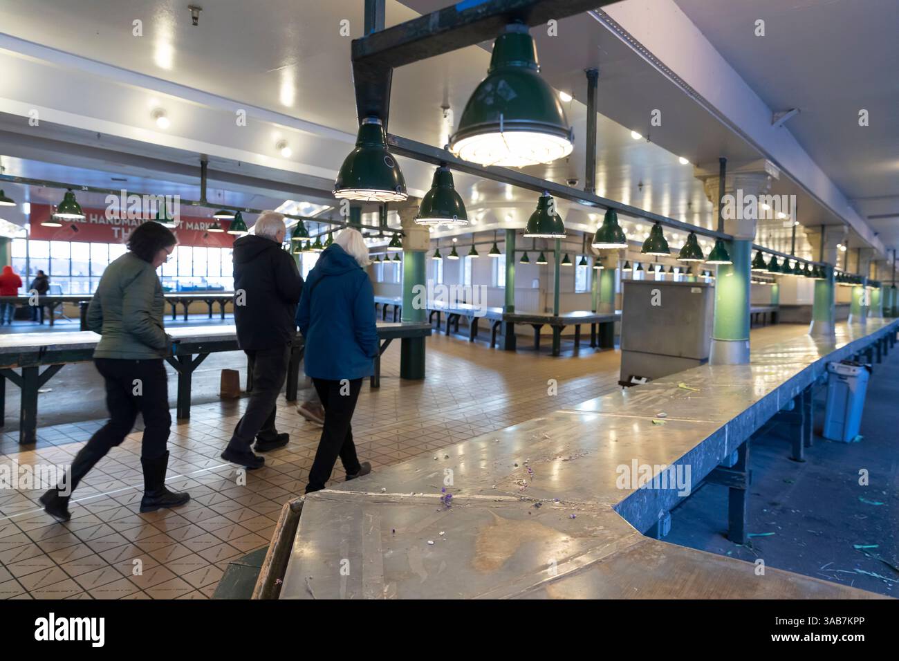 Die Verkaufsstände stehen leer, während die verbleibenden Besucher den Pike Place Market nach Geschäftsschluss in Downtown Seattle verlassen. Stockfoto