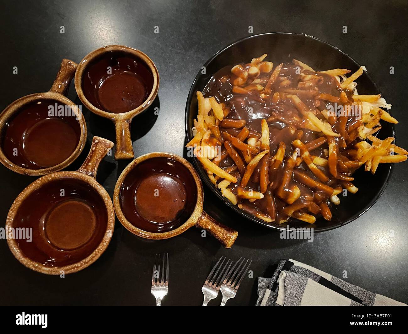 Köstlicher kanadischer Poutine in einer Schüssel mit knusprigen goldenen Pommes frites, Käsequark und kräftiger brauner Soße. - Smartphone-aufgenommenes Stockfoto