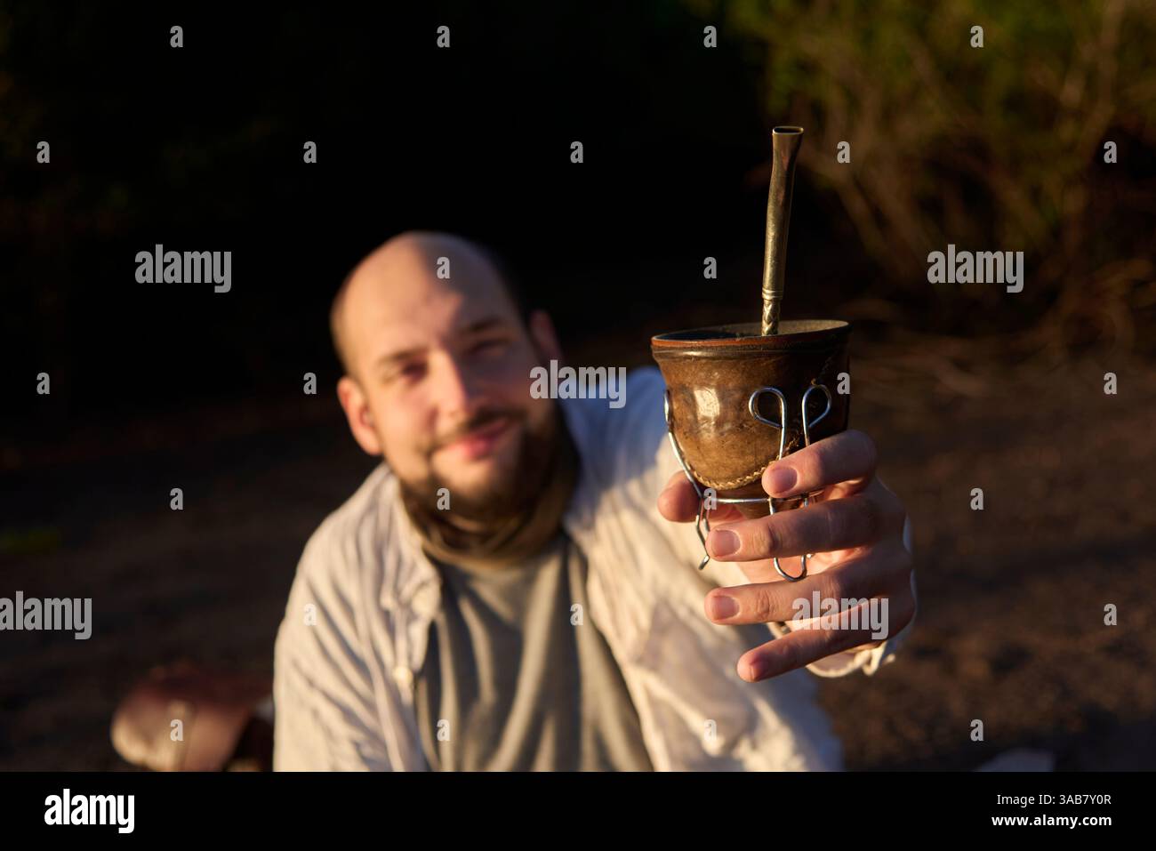Ein lächelnder Mann bietet der Kamera einen Kameraden an. Dieses argentinische Getränk ist ein Symbol für das Teilen und Zusammensein. Komposition mit selektivem Fokus auf den han Stockfoto