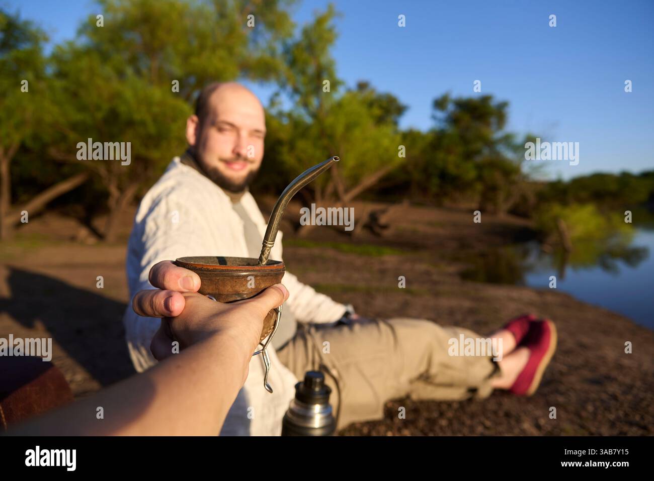 Ein lächelnder Mann trinkt mit jemandem. Dieser argentinische Aufguss ist ein Symbol für das Teilen und Zusammensein. Komposition mit selektivem Fokus auf den han Stockfoto