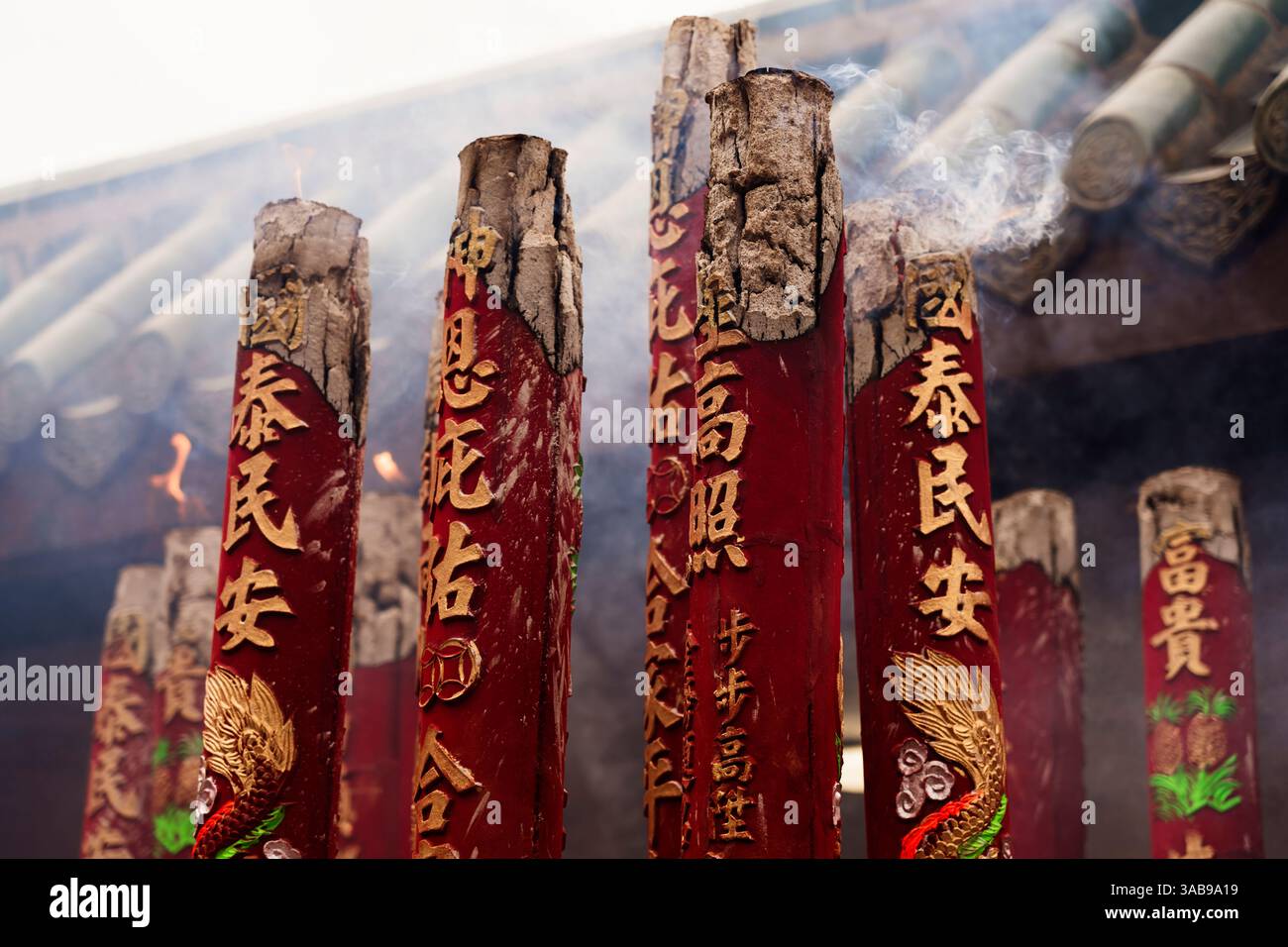 Nahaufnahme großer roter Räucherstäbchen mit detaillierten Schnitzereien, die während der chinesischen Neujahrsfeier in Hongkong schwelen. Stockfoto