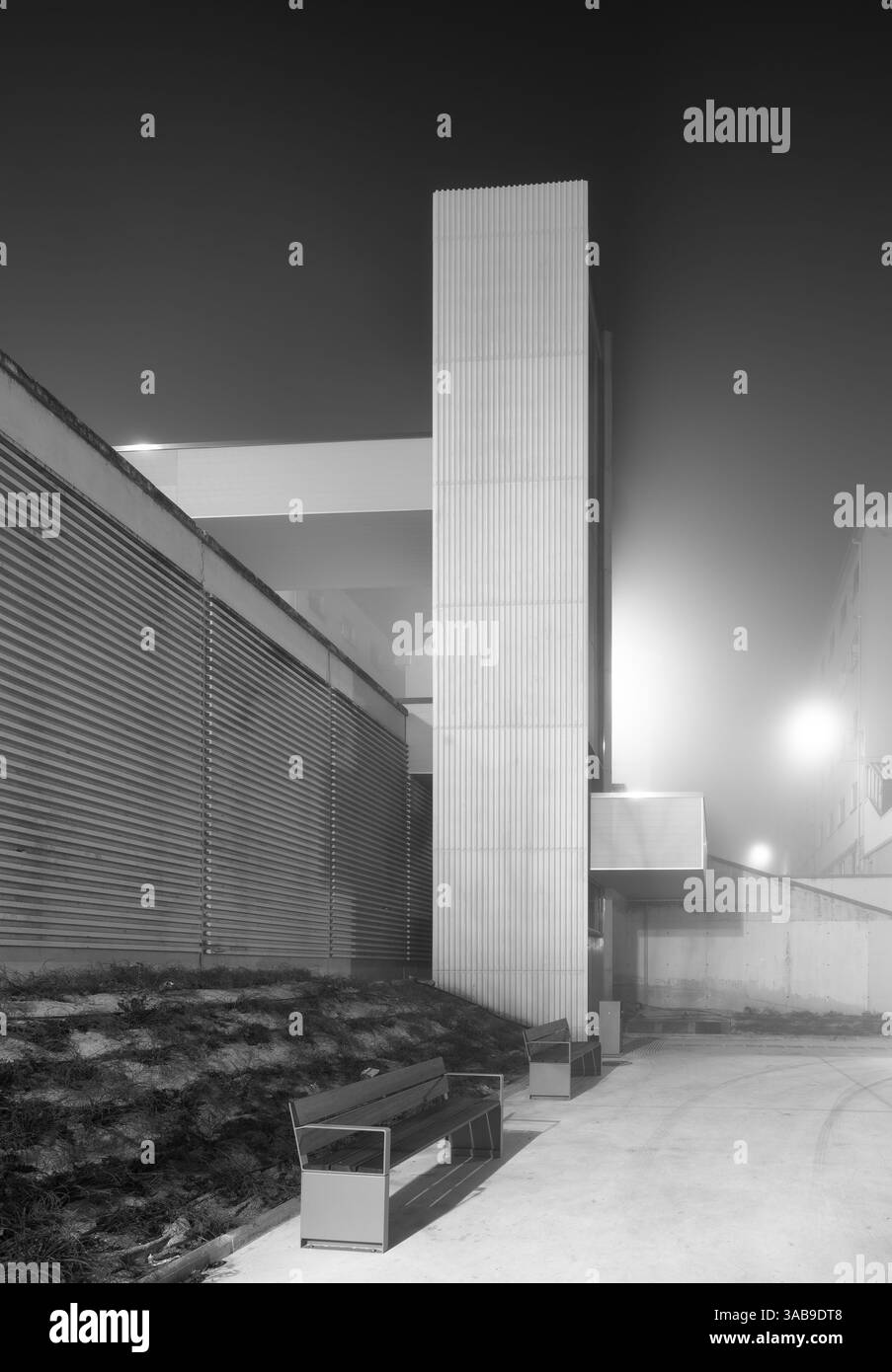 In Nebel und Nebel taucht ein städtischer Aufzug auf, der bei Nacht dezent beleuchtet wird. Das moderne Design steht im Kontrast zur natürlichen Weichheit der nebeligen Umgebung Stockfoto