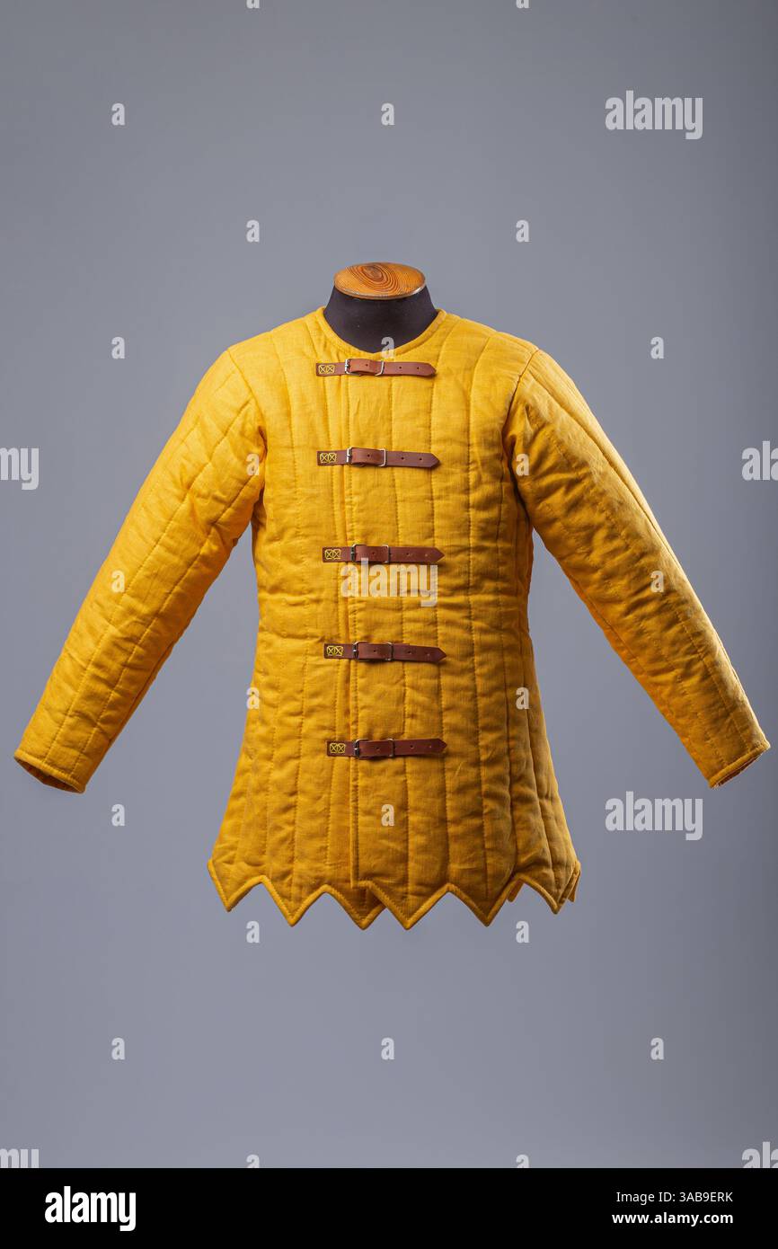 Gelbe Gepolsterte Gambeson-Jacke. Gesteppte Unterpanzerung im Mittelalter mit Lederriemen. Stockfoto