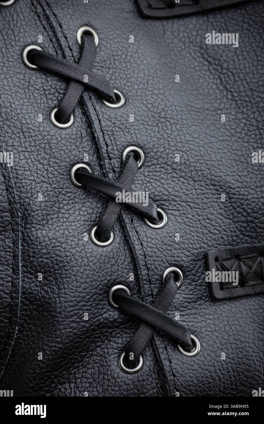Nahaufnahme der Schnürung der schwarzen Lederjacke. Diese Abbildung zeigt eine Nahaufnahme des dekorativen Schnürdetails an der Seite der ärmellosen jacke aus schwarzem Leder Stockfoto