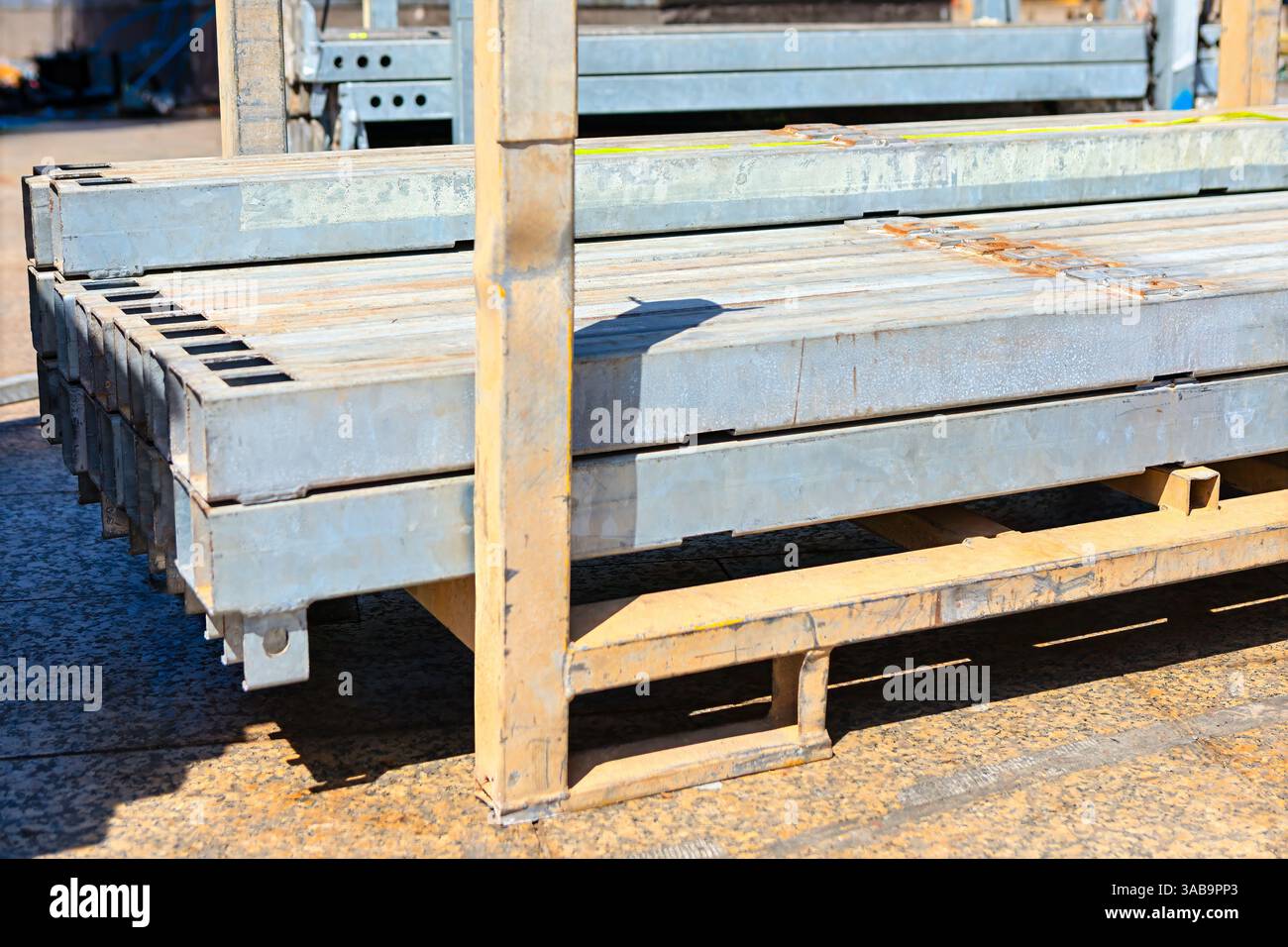 Stapel von Metallträgern, ordentlich auf einem Metallregal angeordnet, Palette von Industrie- und Baueinrichtungen. Einige Balken weisen Rostflecken auf, was darauf hindeutet Stockfoto