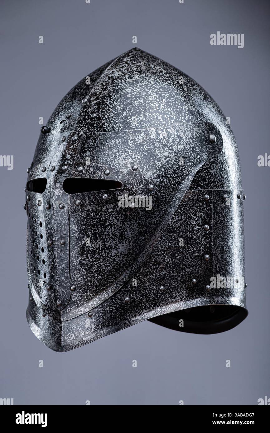 Geschlossener mittelalterlicher Ritterhelm mit kleinen Perforationen. Dieses Bild zeigt einen geschlossenen mittelalterlichen Ritterhelm, wahrscheinlich aus Stahl, mit einer spitzen Spitze Stockfoto