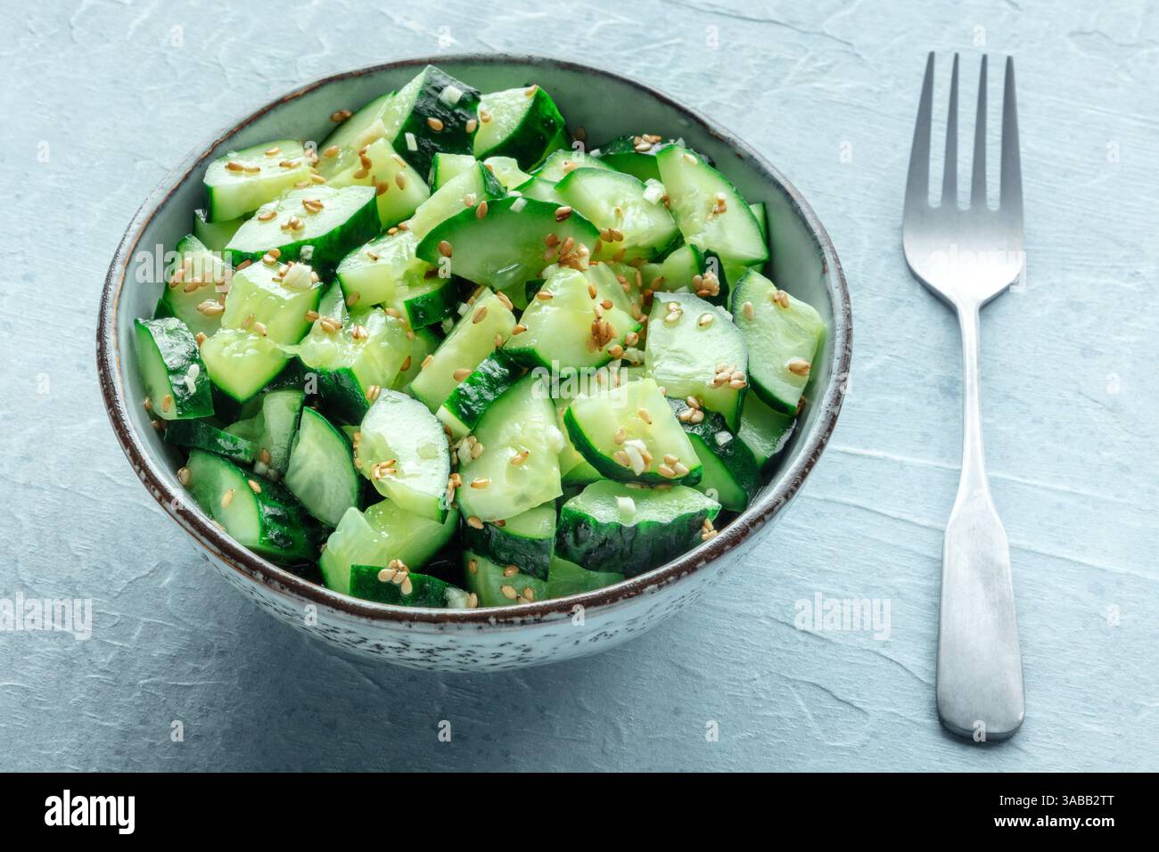 Zerstoßener Gurkensalat, gesundes veganes Essen, grüner Snack, auf Schiefergrund mit einer Gabel Stockfoto