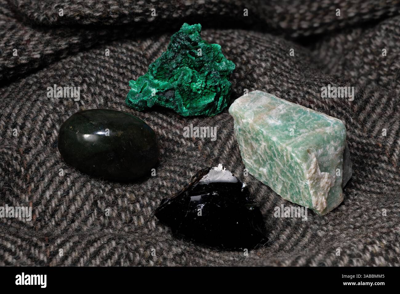 Auswahl an natürlichen polierten und rohen Edelsteinen auf weichem grauen Texturhintergrund. Stockfoto