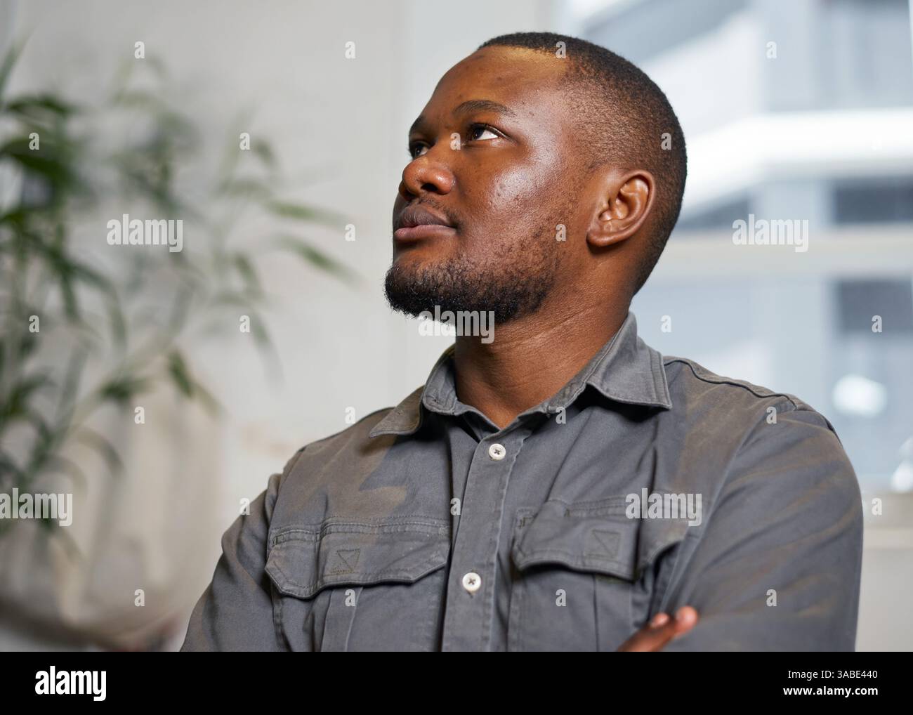 Nachdenklicher junger Mann, der in einer Innenumgebung aufblickt und Ideen erwägt Stockfoto